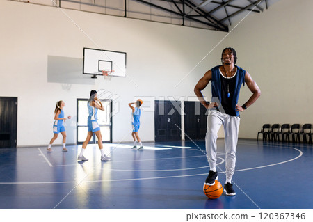Male african american basketball coach with female players practicing, copy space 120367346