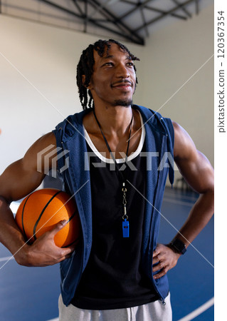 Holding basketball, coach standing confidently in school gymnasium Holding basketball, coach standing confidently in school gymnasium 120367354