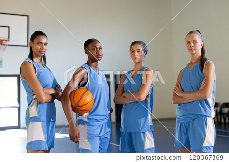 Posing confidently in gym, female basketball team holding basketball Posing confidently in gym, female basketball team holding basketball 120367369