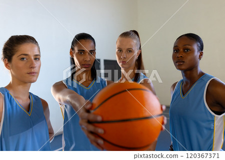 Holding basketball, female basketball team posing confidently in sports uniforms 120367371