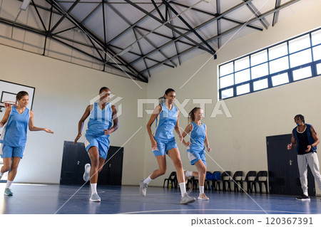 Playing basketball, female team practicing on court with coach in school gym 120367391