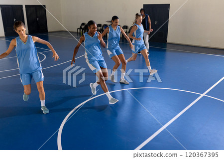 Female basketball team practicing drills on indoor court, focusing on coordination, copy space 120367395