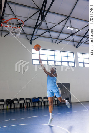 Playing basketball, woman in blue uniform making layup in gymnasium, copy space 120367401