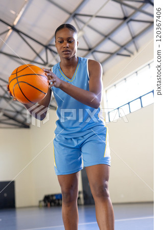 Playing basketball, woman in sportswear focusing on dribbling in indoor court Playing basketball, woman in sportswear focusing on dribbling in indoor court 120367406