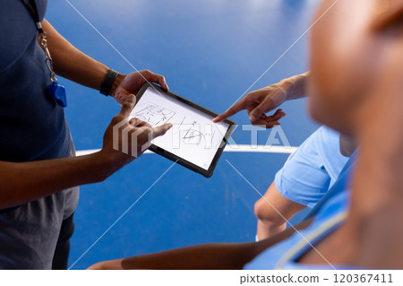 Basketball male coach using tablet to discuss game strategy with players Basketball male coach using tablet to discuss game strategy with players 120367411