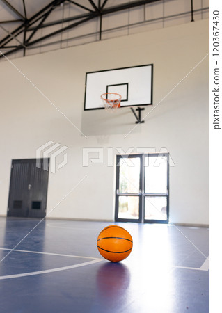 Basketball on court in gymnasium with hoop in background, ready for game, copy space Basketball on court in gymnasium with hoop in background, ready for game, copy space 120367430