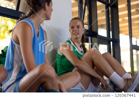 Resting after basketball game, two women in sports jerseys talking on bench Resting after basketball game, two women in sports jerseys talking on bench 120367441