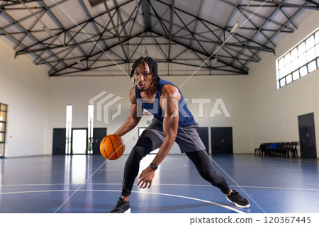 Dribbling basketball, african american man practicing on indoor court, focused on training 120367445