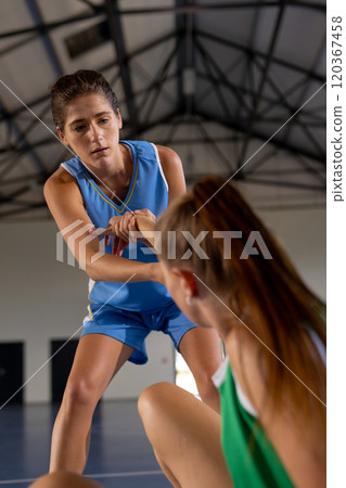 Helping teammate up, female basketball players in sports uniforms on court Helping teammate up, female basketball players in sports uniforms on court 120367458