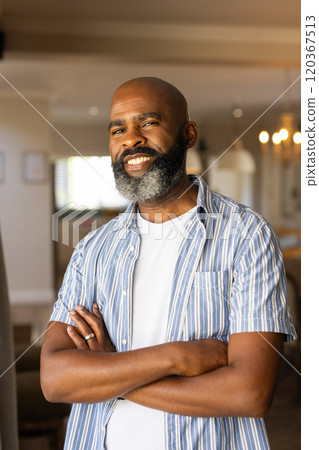 Smiling african american senior man with crossed arms standing confidently in modern home Smiling african american senior man with crossed arms standing confidently in modern home 120367513