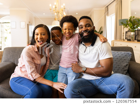Smiling family sitting on couch, enjoying quality time together at home 120367554