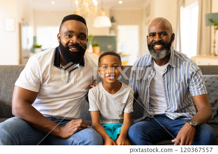 Smiling family sitting on couch, two men and young boy enjoying time together Smiling family sitting on couch, two men and young boy enjoying time together 120367557
