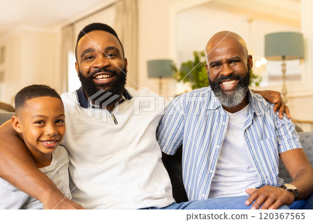 Smiling family of three generations sitting together on couch at home 120367565