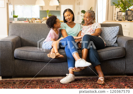 Sitting on couch, multi-generational family bonding and smiling in living room, copy space 120367570
