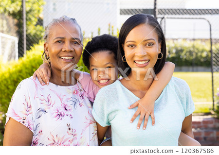 Smiling family outdoors, grandmother, mother, and daughter enjoying time together 120367586