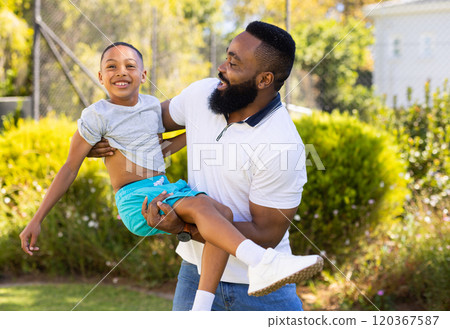 Lifting and playing with son, father smiling and enjoying time outdoors together Lifting and playing with son, father smiling and enjoying time outdoors together 120367587
