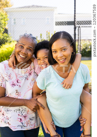 Smiling family outdoors, grandmother, mother, and daughter enjoying time together 120367589