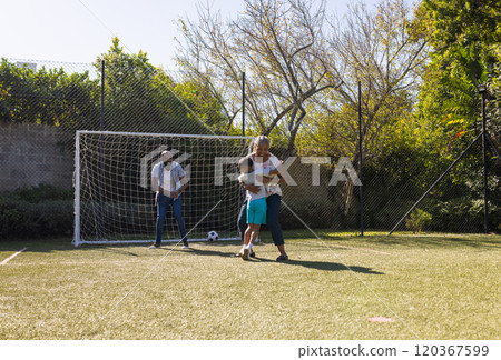 Playing soccer in backyard, grandparents and grandson enjoying time together outdoors 120367599