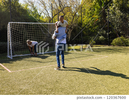 Playing soccer, grandparents and grandson enjoying time together on backyard field with goal net 120367600