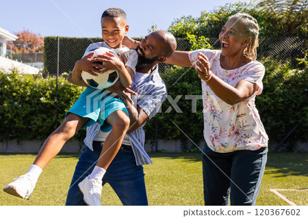 Playing with soccer ball, grandparents and grandson enjoying outdoor time together in backyard 120367602