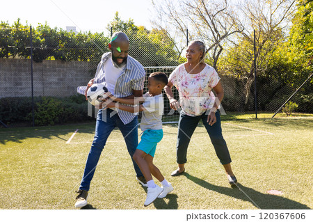 Playing soccer in backyard, grandparents and grandson enjoying outdoor time together Playing soccer in backyard, grandparents and grandson enjoying outdoor time together 120367606