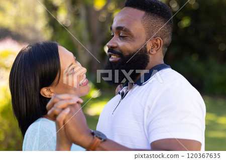 Couple holding hands and smiling at each other in outdoor setting Couple holding hands and smiling at each other in outdoor setting 120367635