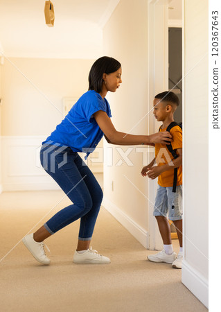 Helping child with backpack, woman preparing boy for school in hallway 120367643