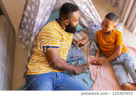 Father and son talking and bonding in cozy indoor tent teepee setup at home 120367655