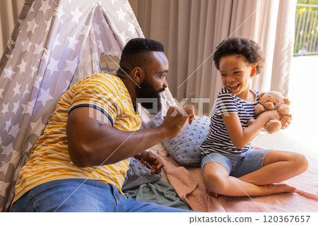 Playing with stuffed animal, father and daughter enjoying quality time indoors, in teepee Playing with stuffed animal, father and daughter enjoying quality time indoors, in teepee 120367657