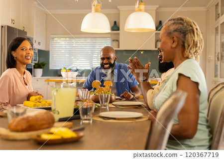 multigenerational family enjoying meal together, smiling and talking in modern kitchen multigenerational family enjoying meal together, smiling and talking in modern kitchen 120367719