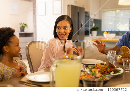 Smiling family enjoying dinner together, sharing stories and bonding at home Smiling family enjoying dinner together, sharing stories and bonding at home 120367722