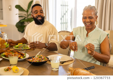 Enjoying multigenerational family meal, smiling man and woman sitting at dining table with food Enjoying multigenerational family meal, smiling man and woman sitting at dining table with food 120367733