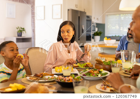 multigenerational family enjoying meal together, sharing food and conversation at dining table 120367749