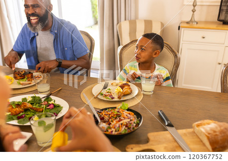 multigenerational family enjoying meal together at dining table, smiling and sharing food 120367752