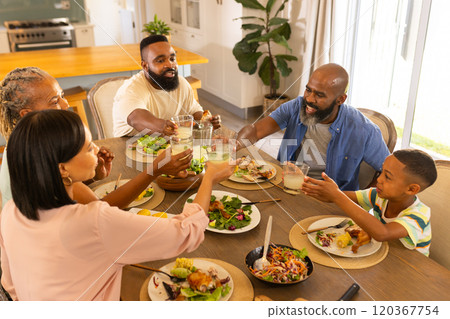 multigenerational family enjoying dinner together, raising glasses for toast at home multigenerational family enjoying dinner together, raising glasses for toast at home 120367754