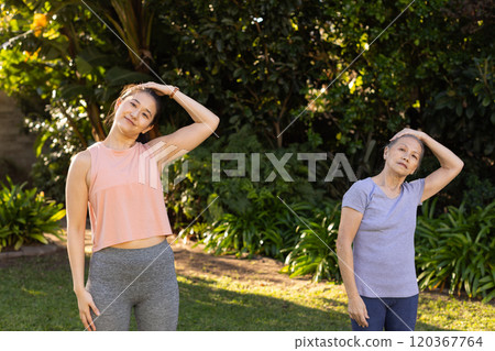 Exercising together, asian grandmother and granddaughter stretching necks outdoors Exercising together, asian grandmother and granddaughter stretching necks outdoors 120367764