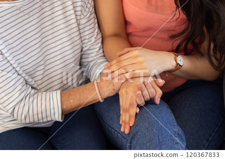 Holding hands, two women showing support and comfort, wearing casual clothes 120367833
