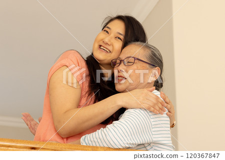 Hugging and smiling, asian grandmother and granddaughter sharing warm moment at home 120367847