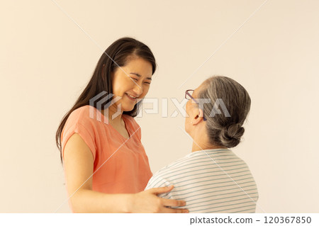 Embracing, smiling asian grandmother and granddaughter sharing joyful moment together Embracing, smiling asian grandmother and granddaughter sharing joyful moment together 120367850