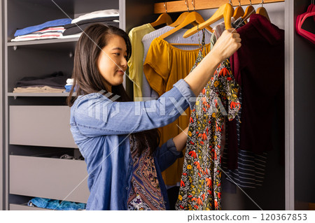 Choosing clothes from wardrobe, Asian woman smiling and deciding on outfit 120367853