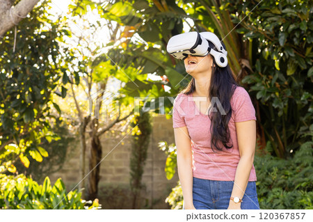 Using VR headset, Asian woman enjoying virtual reality experience outdoors in garden 120367857