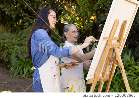 Painting on canvas, Asian granddaughter and grandmother enjoying outdoor art session together Painting on canvas, Asian granddaughter and grandmother enjoying outdoor art session together 120368665
