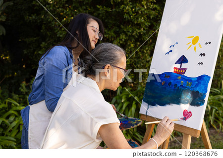 Painting on canvas, asian granddaughter and grandmother creating artwork together Painting on canvas, asian granddaughter and grandmother creating artwork together 120368676