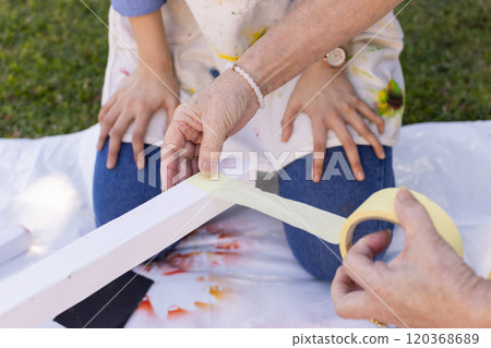 Applying masking tape to wooden plank, person preparing for painting project 120368689