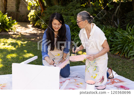 Painting furniture together, asian granddaughter and grandmother bonding in garden Painting furniture together, asian granddaughter and grandmother bonding in garden 120368696