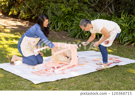 Painting chair outdoors, asian grandmother and gradndaughter collaborating on DIY project in backyar Painting chair outdoors, asian grandmother and gradndaughter collaborating on DIY project in backyar 120368715