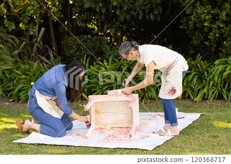 Painting wooden furniture, asian grandmother and gradndaughter working together outdoors on sunny da 120368717