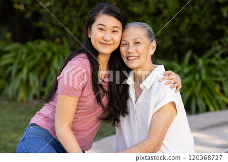 Smiling granddaughter hugging older asian woman outdoors, enjoying quality time together 120368727