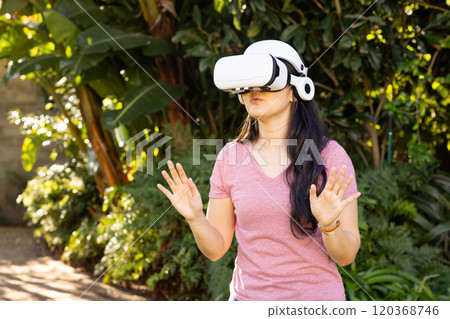 Using VR headset, asian woman exploring virtual reality outdoors in garden 120368746