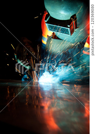 Welder uses torch to make sparks during manufacture of metal equipment, industrial professional worker 120369080
